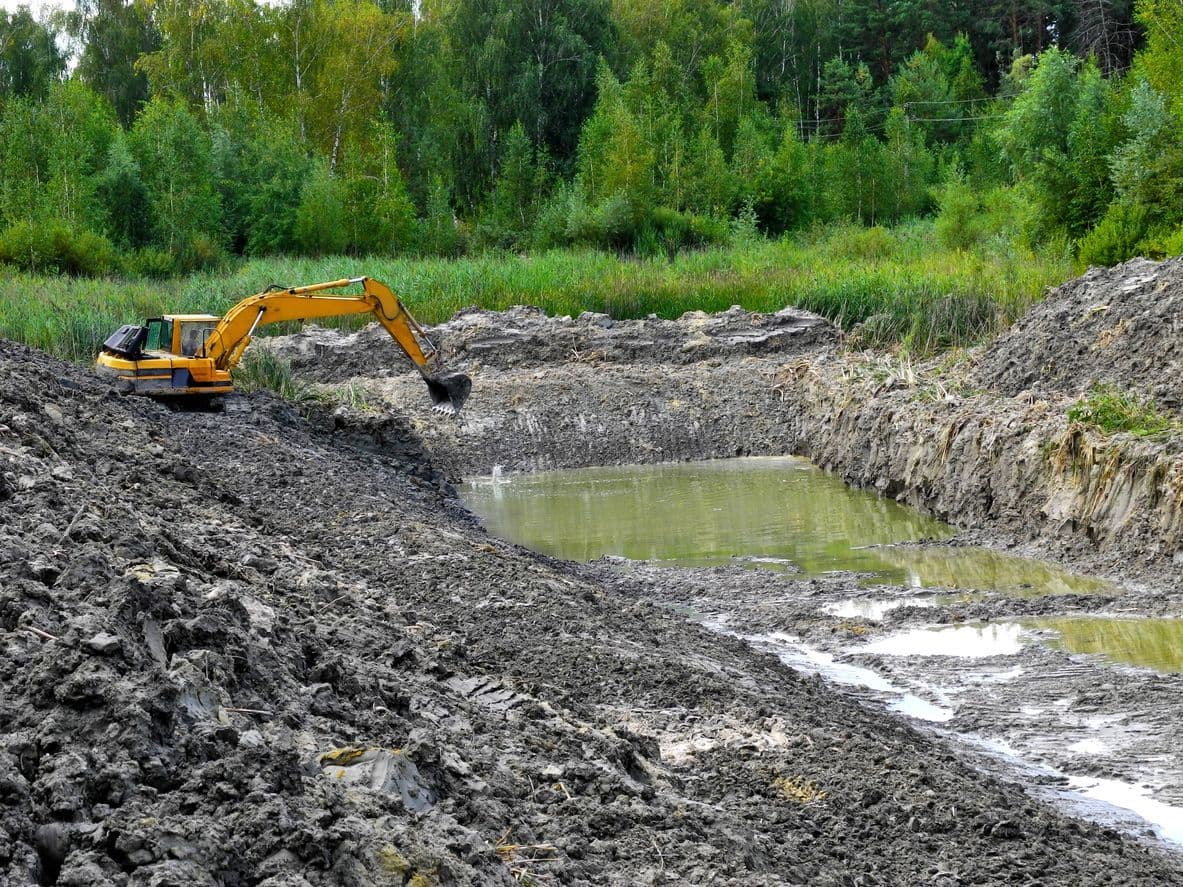 Excavator digging a pond on a rural property